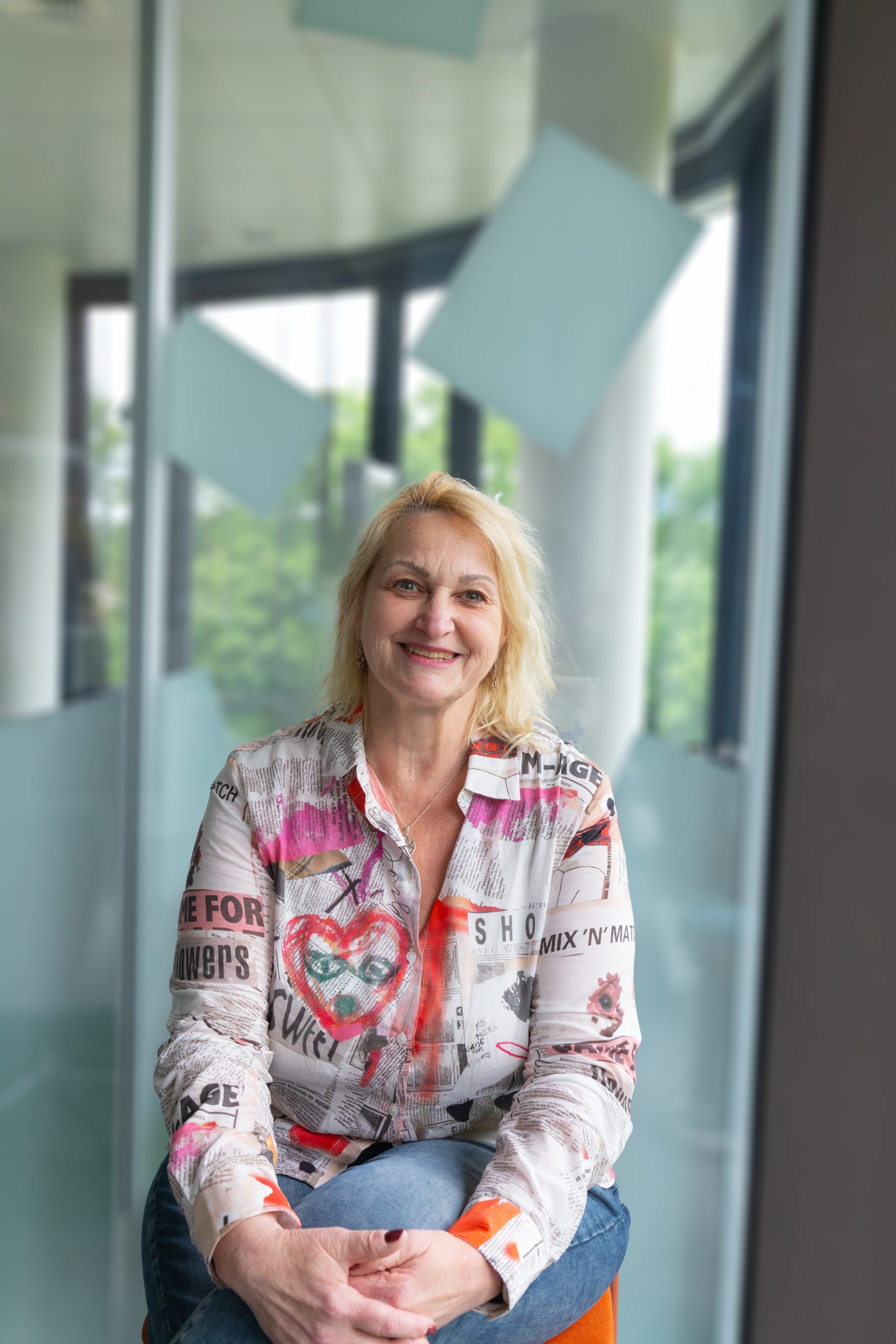 Frau sitzend vor transparenter Glasfront.
